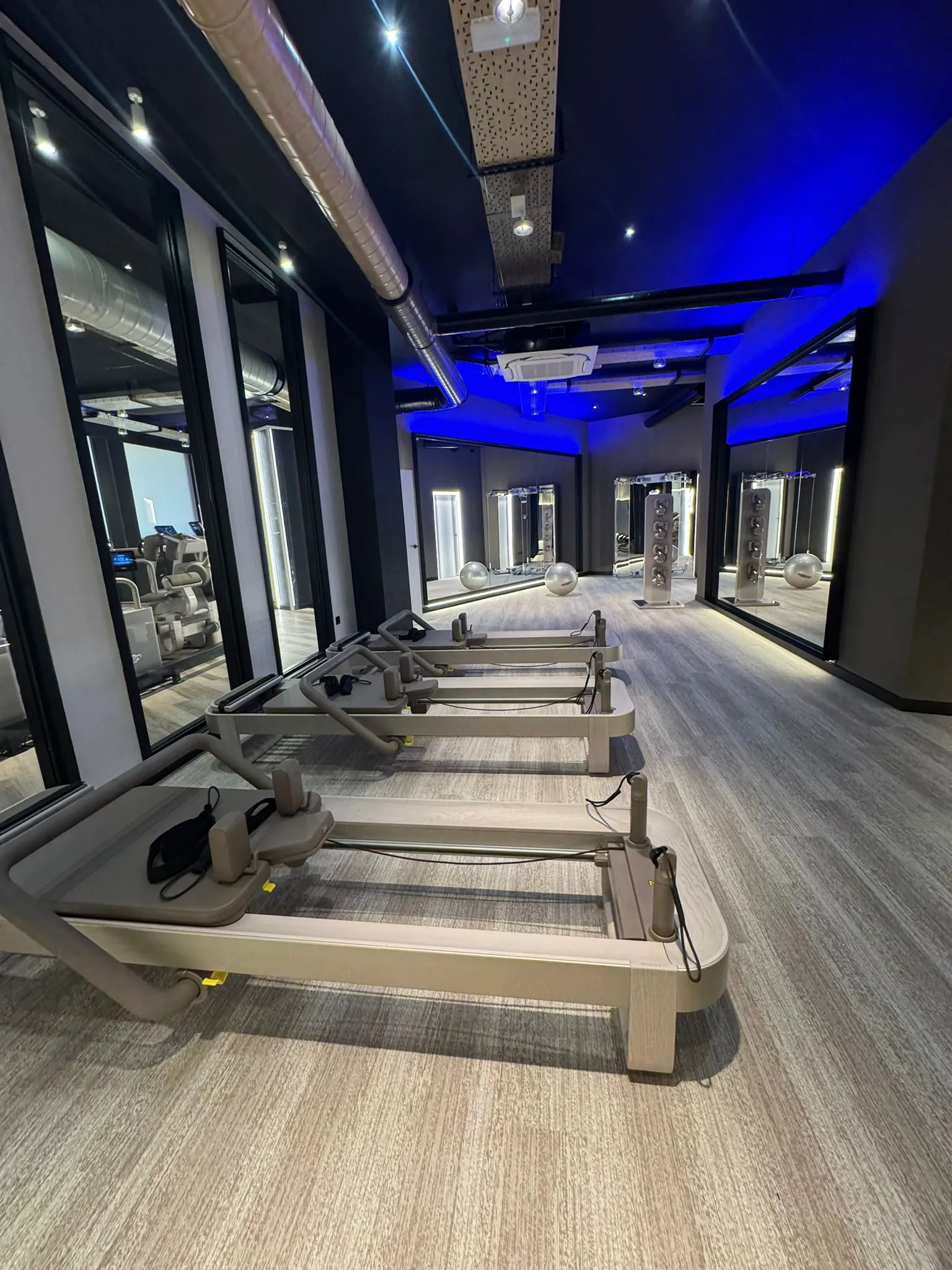 Sala de Pilates Reformer amb cinc reformers Technogym i llum blava cenital.